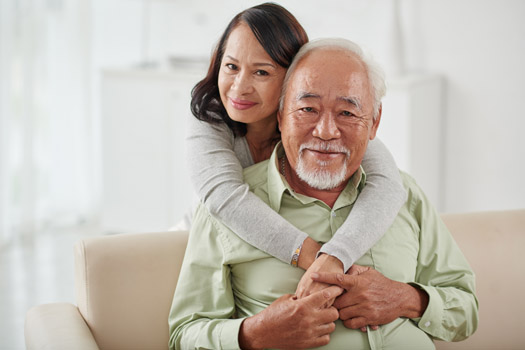 Happy smiling aged woman hugging her husband from behind