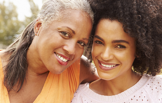 Portrait Of Mother With Adult Daughter In Park Smiling To Camera