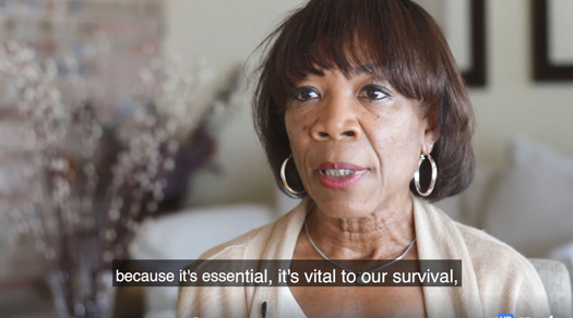 Screen shot of video with Zelda Foxall. Captioning across the bottom read "... because it's essential, it's vital to our survival."
