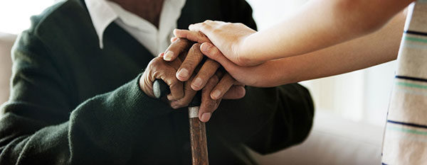 caregiver resting their hands on elderly person's hands