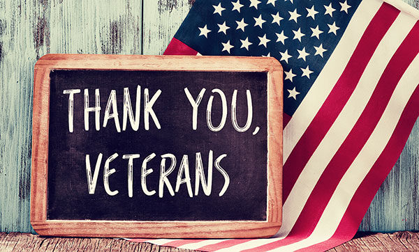 Chalkboard with "Thank You Veterans" written on it with American flag in the background
