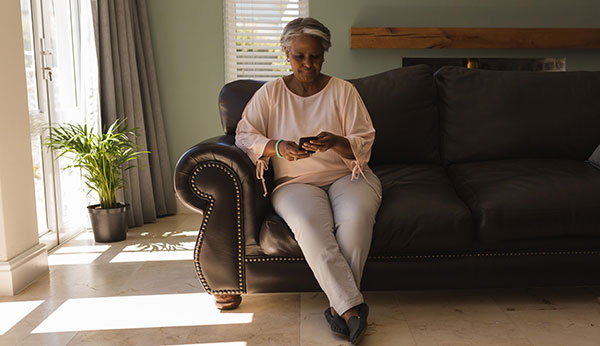 woman sitting on a couch looking at her smart phone