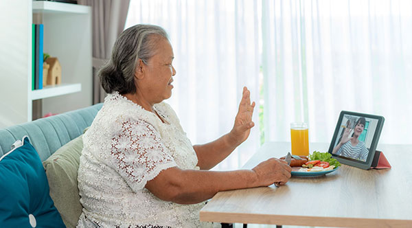 elderly woman eating breakjfast while on a video call