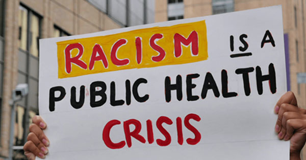 Protestor holding up Racism is a public health crisis sign