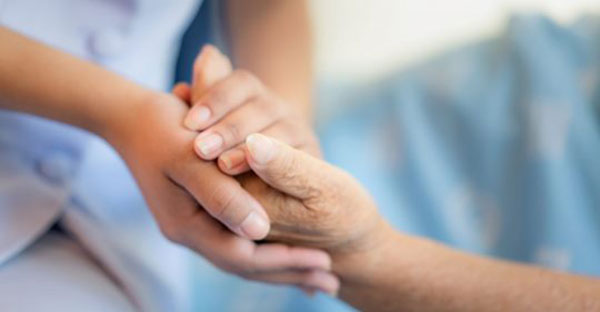 caregiver holding elderly woman's hand