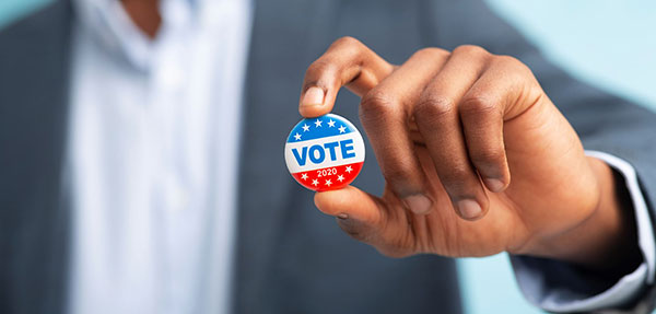 man in suite holding a Vote button