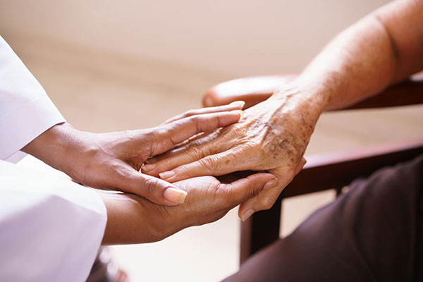 close up of caregiver holding elderly person's hand