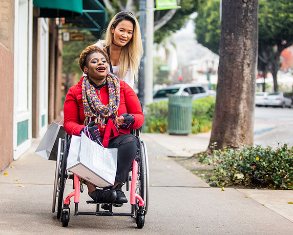 young woman pushging elderly woman in a wheelchair