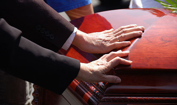hands resting on a coffin