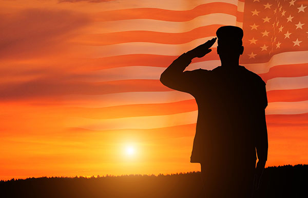 veteran saluting in front of a sunset