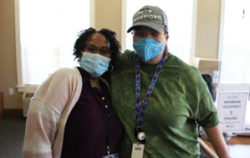 A black woman and white man stand with masks on in a long-term care facility.