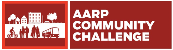 A decorative red and white image featuring a white neighborhood icon and bold sans serif white text that reads "AARP COMMUNITY CHALLENGE."