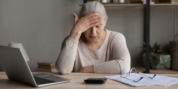Worried upset older woman sit at table with laptop, counts expenses, manage budget, check bills for payment, thinks on financial problems, looks stressed due to lack of money, huge monthly fee concept