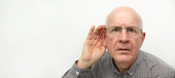 Senior suffering from deafness. Man asks to repeat the question. Wide copy space image for web banner background
