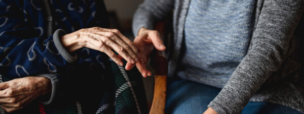 Unrecognizable young person taking hands of old woman. Elderly, care, family concept.