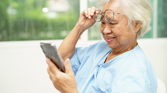 Asian senior woman wearing eyeglasses or vision glasses using a smartphone at home care service.