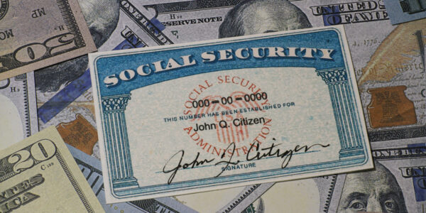 Lake Elsinore, CA, USA - January 30, 2022: Fake Social security card on prop US currency - Concept of Social Security Benefits