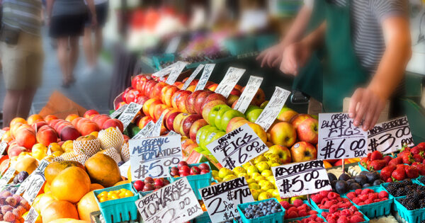Fruits with tag prices on stands in an outdoors fruit market in Seattle, Washington.