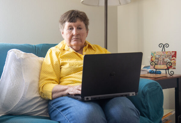 Sue Luke sits on couch with computer