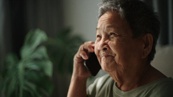Asian senior woman talking on smartphone at home.