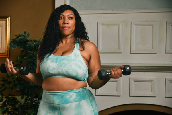 Older woman exercising with dumbells in a home gym.